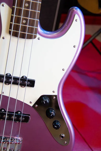 Close up of solid pink purple electric bass guitar with single coil pickups and silver hardware