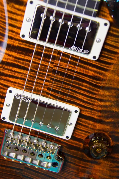 stock image Close up of a solid brown with tiger style wood grain electric guitar, with humbucker pickups, without pickguard and silver hardware.