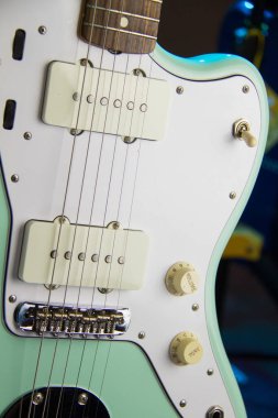 Sağlam bir sörf yeşil elektro gitarı Humbucker pikapları, beyaz yankesicileri ve gümüş donanımları olan yakın çekim..