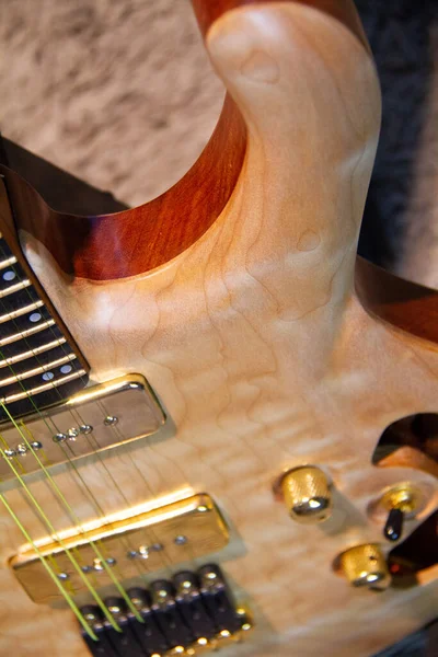 stock image Close up of a solid natural brown electric guitar with humbucker pickups, without pickguard and golden hardware.