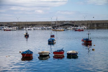 Balıkçı köyü Asturias, Cudillero 'nun limanı, önünde tekneler, güneşli bir günde gökyüzünde bulutlar.