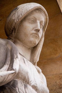 Gijn de Asturias katedralindeki bir bakirenin heykeli, bulutlu bir günün gökyüzü.