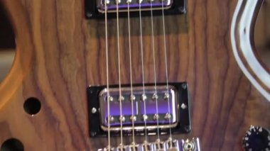 İçi boş bir vücuda yakın. Yankesiciler ve siyah teçhizatsız, humbucker pikaplı doğal kahverengi ahşap gitar..