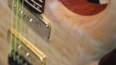 Yankesicisi ve altın donanımı olmayan, humbucker pikaplı, katı kahverengi bir elektro gitarı kapat..