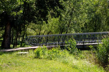 Şehir parkındaki bir gölette açık tırabzan ile hafif bir köprü.