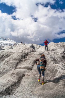Mavi ceketli, sarı şapkalı ve sırt çantalı bir grup turist dağın tepesinde.. 