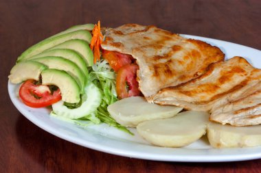 Kızarmış tavuk göğsü ve beyaz tabakta salata..