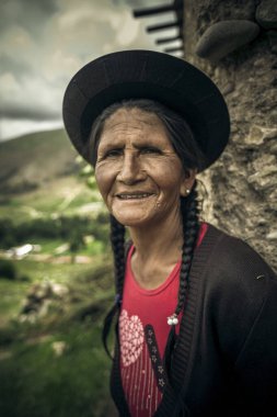 Kafasında şapka ve sırt çantası olan geleneksel elbiseli bir kadın.