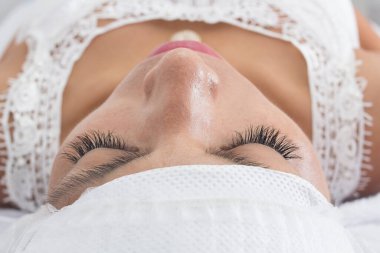 Güzellik salonunda gözleri kapalı genç bir kadın.