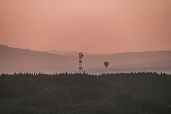Hot air balloon above high mountain at sunrise, sunset. Colorful hot-air balloon flying over the mountain