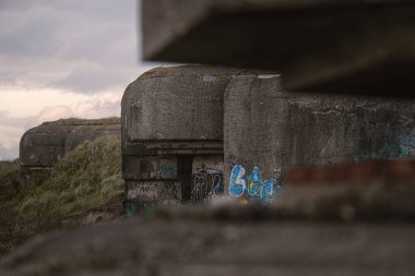 Bunker complex IJmuiden, IJmuiden, North Holland, Netherlands, April 24, 2024: German defense line from the WWII consisting of concrete bunkers and gun emplacements during sunset. clipart