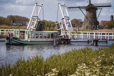 Kindedijk, Hollanda - 24 Nisan 2024: Ünlü Kinderdijk kanalı üzerinde yel değirmenleriyle yürüyen tekne. Eski Hollanda köyü Kinderdijk, UNESCO dünya mirası bölgesi. Hollanda, Avrupa.