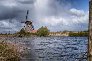 KINDERDIJK, NETHERLANDS-APRIL 24,2024: Tarihsel rüzgar değirmenleri ve Hollanda 'nın Kinderdijk kentinde akan bir nehir. Bu 19 yel değirmeninden oluşan sistem 1740 'larda inşa edildi ve UNESCO' nun mirası haline geldi..