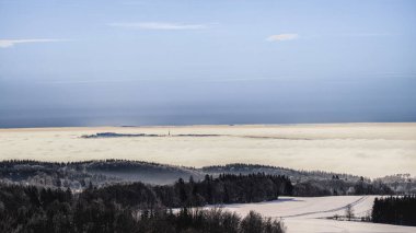 Çek Dağları 'nda muhteşem bir kış sisli bir sabah. Gri tersini ve kirli hava katmanının üstündeki karlı arazi tepeleri..