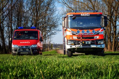 Castolovice, Çek Cumhuriyeti - 12 Nisan 2025: Çayırda gün batımında iki itfaiye aracı.