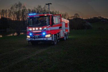 Castolovice, Çek Cumhuriyeti - 12 Nisan 2025: Yeni itfaiye aracı İskandinav CAS30 9000 510 S2R bir çayır üzerinde gün batımında.