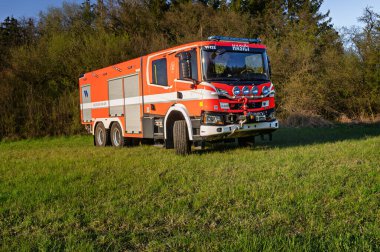 Castolovice, Çek Cumhuriyeti - 12 Nisan 2025: Yeni itfaiye aracı İskandinav CAS30 9000 510 S2R bir çayır üzerinde gün batımında.