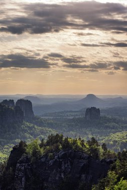 Almanya 'da Carolafelsen, kumtaşı uçurumundan Saksonya İsviçre' nin derin sisli vadisine güzel bir akşam manzarası. Kumtaşı zirveleri sisli arka plandan yükseldi. Vahşi doğada akşam manzarası..