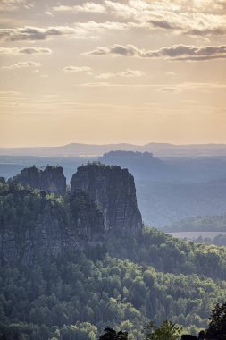 Almanya 'da Carolafelsen, kumtaşı uçurumundan Saksonya İsviçre' nin derin sisli vadisine güzel bir akşam manzarası. Kumtaşı zirveleri sisli arka plandan yükseldi. Vahşi doğada akşam manzarası..