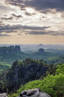 Almanya 'da Carolafelsen, kumtaşı uçurumundan Saksonya İsviçre' nin derin sisli vadisine güzel bir akşam manzarası. Kumtaşı zirveleri sisli arka plandan yükseldi. Vahşi doğada akşam manzarası..