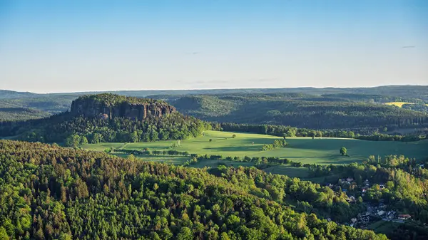 Günbatımı, Lilienstein 'da görüldüğü gibi Sakson İsviçre' nin verimli bahar manzarasına ılık bir ışıltı yayar. Tarlalar ve ormanlar genişliyor, dingin ve görkemli bir zemin oluşturuyor..