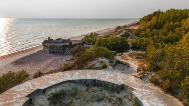 Klaipeda, Litvanya - 4 Haziran 2025: Memel Nord bataryasının insansız hava aracı fotoğrafçılığı - Yaz akşamı kıyı kenarında 2. Dünya Savaşı sığınağı.