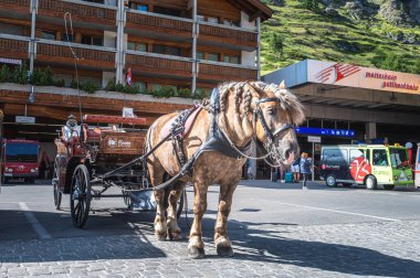 ZERMATT, SWitzERLAND - 26 Ağustos 2021: İsviçre 'nin Valais kantonundaki Zermatt kasabasının merkezindeki at antrenörü ve geleneksel yerel evler