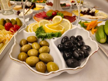 Beyaz tabakta zeytin ve sebzeli aperatif.