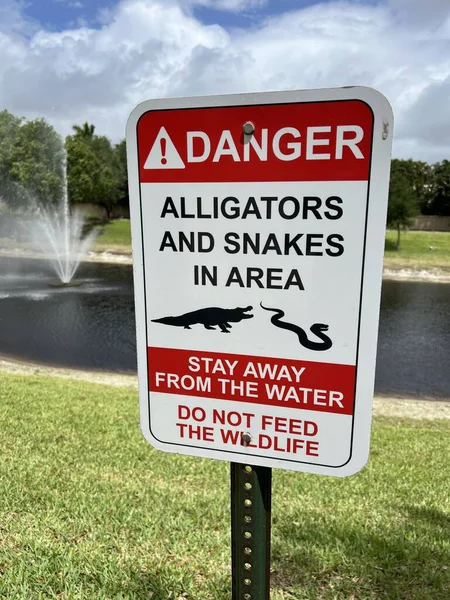 有一个绿色草坪的红色标志 Alligators Snakes Area — 图库照片
