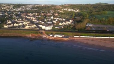 Goodrington Sands, Torbay, Güney Devon, İngiltere: Drone Views: Güney Sands kafesini, plajı, denizi, yakındaki evleri, Torbay VeloPark 'ı, VeloPark' ı ve Paignton kasabasını göstermek için gezinti alanından uzaklaşın..