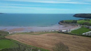 Broadbay, Torbay, Güney Devon, İngiltere: DRONE VİEWS: İHA Broadsand sahiline doğru tarlaya iniyor. Torbay Denizi ve Brixham 'a giden kıyı şeridi arka planda..