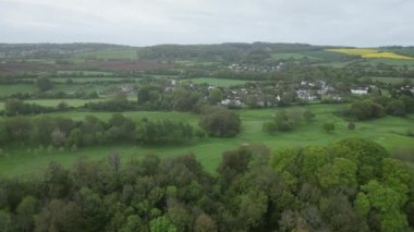 Churston, Güney Devon, İngiltere: DRONE AERIAL VİEWS: Arka planda kolza yağı (yağ tohumu tecavüz) tarlaları, ön planda Churston Ferrers köyü ve ön planda Churston golf sahası gösteren sağdan sola doğru izler.