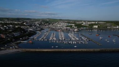 Brixham, Torbay, Güney Devon, İngiltere: DRONE AERIAL VİEWS: İHA arka planda Brixham marinası, yatları ve tekneleri ve Brixham balıkçı köyü olan dış liman duvarına doğru uçar.