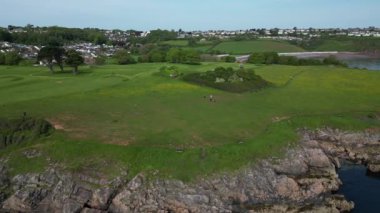 Torbay, Güney Devon, İngiltere: DRONE AERIAL VİEWS: Broadsand ve Elberry Cove arasındaki kıyı şeridi; Broadsand plajı arka planda (resmin sağında) görünürken İHA engebeli kıyı şeridini izlemeye devam etmektedir ().