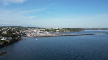 Brixham, Torbay, Güney Devon, İngiltere: DRONE AERIAL VİEWS: Dış Liman duvarının ön plandaki görüntüsü, insansız hava aracı ona doğru uçarken - Brixham marinası ve Brixham balıkçı köyü arka planda yükselir; insansız hava aracı yüksek açılı görüş için yükselir