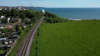 Broadbay, Torbay, Güney Devon, İngiltere: DRONE AERIAL VİEWS: İnsansız hava aracı Kingswear 'e giden bir buhar trenine doğru uçuyor ve ünlü Victoria dönemi inşaat mühendisi Isambard Kingdom Brunel tarafından tasarlanan demiryolu viyadük köprüsünün yan görüntüsünü veriyor.. 