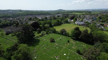 Highweek, Newton Abbot, Güney Devon, İngiltere: DRONE AERIAL VİEWS: İHA All Saints Kilisesi ve ön plandaki mezarlığıyla Highweek köyünü göstererek sağdan sola uçuyor. Uzakta Dartmoor Ulusal Parkı (Clip 2).