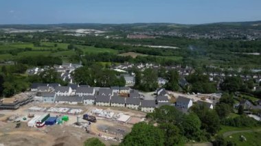 Newton Abbot, Güney Devon, İngiltere: DRONE AERIAL VİEWS: Kısmen inşa edilmiş evler, tamamlanmış evler ve vakıflarla yeşil kuşak üzerinde yeni bir inşaat sahası. Dartmoor Milli Parkı 'na doğru bakan kırsal bölge (Bölüm 4).