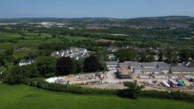 Newton Abbot, Güney Devon, İngiltere: DRONE AERIAL VİEWS: Kısmen inşa edilmiş evler, tamamlanmış evler ve vakıflarla yeşil kuşak üzerinde yeni bir inşaat sahası. Dartmoor Milli Parkı 'na doğru bakan kırsal bölge (Bölüm 2).