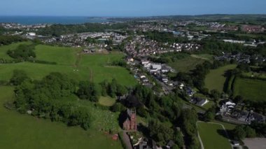 Collaton St Mary, Güney Devon, İngiltere: DRONE AERIAL VİEWS: İHA yeşil kuşak arazisini göstermek için St. Mary kilisesi ve Collaton St. Mary köyünden uzaklaşır; Paignton ve Torbay denizi arka plandadır. 