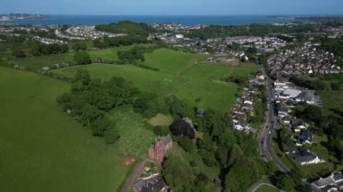 Collaton St Mary, Güney Devon, İngiltere: DRONE VİEWS: İHA St. Mary kilisesine doğru uçar ve Totnes Yolu boyunca arabaları / trafiği gösterir; arka planda ise kıyı kenti Paignton ve Torbay kıyı şeridi bulunur..