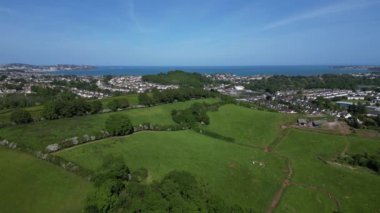 Collaton St Mary, Güney Devon, İngiltere: DRONE AERIAL VİEWS: İHA, Torbay ve Torbay kıyı şeridinde denizi görmek için yükselmeden önce Collaton Saint Mary köyü yakınlarındaki yeşil kuşak ülke tarlalarını gösteriyor (Klip 2).