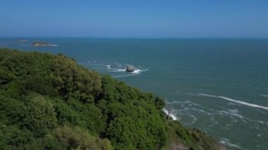 Torquay, Torbay, Güney Devon, İngiltere: DRONE AERIAL VİEWS: İnsansız hava aracı Shag Rock, Thatcher Rock ve Orestone Rock 'ın uzak çekim görüntüsünü ortaya çıkarmak için ağaçların arkasına yükselir.