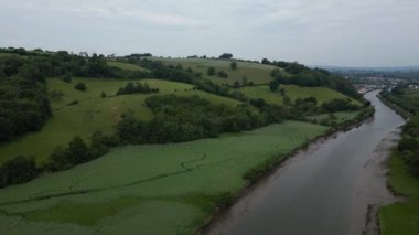 Totnes, Güney Devon, İngiltere: DRONE VIEWS: İnsansız hava aracı nehir dartı, vadisi, tepeleri ve ormanlık üzerinde güneyden kuzeye uçuyor ve uzaktaki Totnes kasabasını görüyor (Klip 1)).