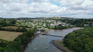 Stoke Gabriel, Güney Devon, İngiltere: DRONE AERIAL VİEWS: İnsansız hava aracı nehir dartlarında demirlemiş teknelerin üzerinden yükseklere uçuyor ve arkada Stoke Gabriel köyüyle birlikte Mill Pond Weir 'e doğru ilerliyor.