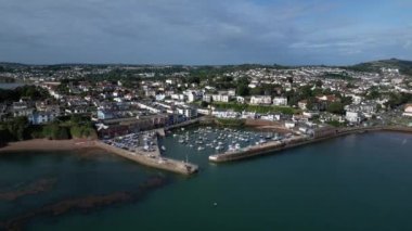 Paignton, Torbay, Güney Devon, İngiltere: İHA arka planda Paignton Limanı girişi, deniz ve Paignton kasabasını gösteren tekne ve yatlara doğru uçuyor. Paignton popüler bir tatil beldesidir (Klip 2).