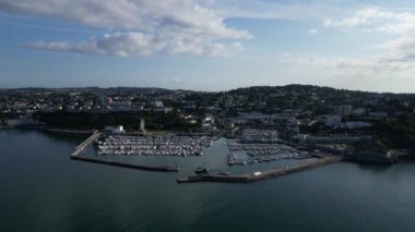 Torquay, Torbay, Güney Devon, İngiltere: DRONE VİEWS: İHA, liman girişine doğru uçan Torquay şehrini yüksek bir açıdan gösteriyor; limanın içinde iki trol manevrası ve bir zevk gemisi yola çıkıyor. Torquay, İngiltere 'de popüler bir tatil beldesi..