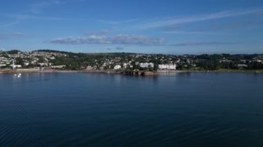Torquay, Torbay, Güney Devon, İngiltere: DRONE VİEWS: İnsansız hava aracı Corbyn Head ve Corbyn Beach 'e doğru uçuyor. Corbyn Sahili 'nin arkasında iki büyük, beyaz bina var, sağ tarafı Grand Hotel. Torquay, turistlerin yaşadığı popüler bir İngiltere tatil beldesi..