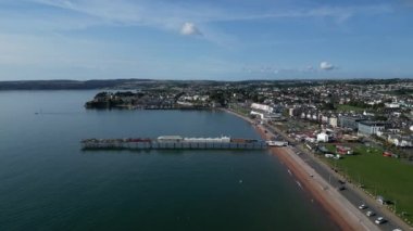 Paignton, Torbay, S. Devon, İngiltere: DRONE VİEWS: İHA, uzaktaki Paignton Rıhtımı, kıyısı ve Torbay kıyı şeridi, Roundham Head dahil olmak üzere yüksek bir görüş için Paignton İskelesi 'ne doğru uçar. Paignton, İngiltere 'nin popüler tatil beldesidir..