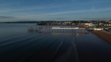 Paignton, Torbay, Güney Devon, İngiltere: DRONE VİEWS: Hafif dalgalar kıyıya ulaşırken İHA doğrudan Paignton İskelesi 'ne doğru uçar. Paignton, İngiltere 'de popüler bir turist ve turistik tatil beldesidir.).